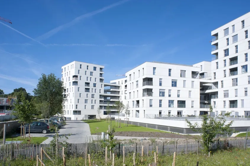 Les 124 logements sont groupés dans deux immeubles en tripodes implantés au-dessus d’un parking semi-enterré.
