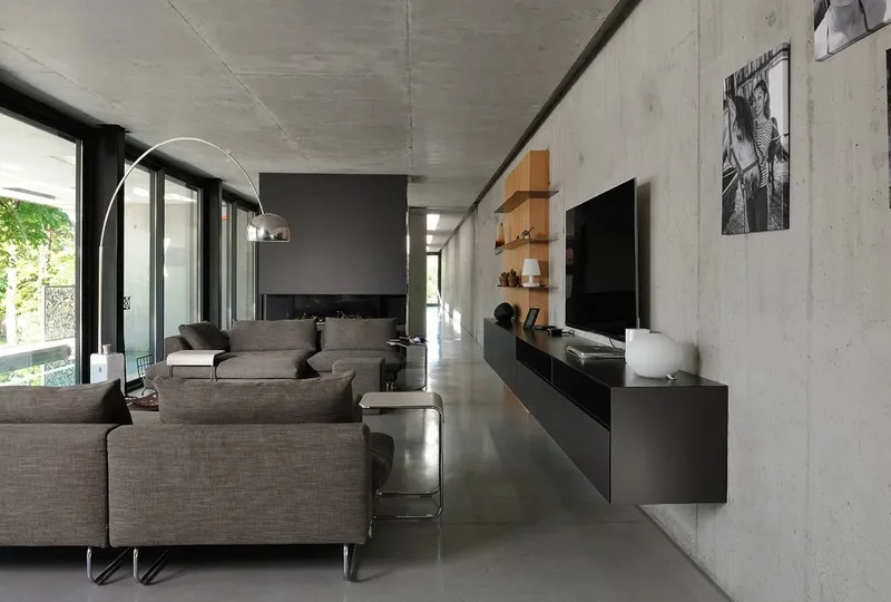 Le béton brut et la lumière naturelle caractérisent tous les espaces intérieurs. Vue sur le séjour et le couloir qui traverse la maison dans toute sa longueur. Le béton brut et la lumière naturelle caractérisent tous les espaces intérieurs. Vue sur le séjour et le couloir qui traverse la maison dans toute sa longueur.
