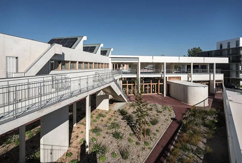 Le jardin met à distance la voie publique des salles de cours. le volume ovoïde en avant de la façade sud délimite l’entrée particulière de la salle de sport. Le jardin met à distance la voie publique des salles de cours. le volume ovoïde en avant de la façade sud délimite l’entrée particulière de la salle de sport.