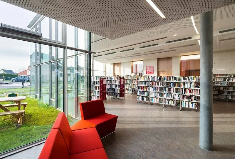 Salle de lecture et d’écoute de la médiathèque entièrement vitrée sur le jardin. les poteaux en béton implantés en retrait de la façade, signalent la structure. Salle de lecture et d’écoute de la médiathèque entièrement vitrée sur le jardin. les poteaux en béton implantés en retrait de la façade, signalent la structure.