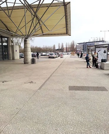 L’entrée du marché couvert, côté nord de la rue du 4-Septembre. De vastes trottoirs en béton bouchardé de couleur beige clair donnent accès au nouveau pôle d’échanges « bus ». marché