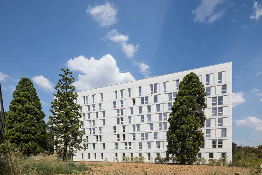 La façade ouest, plus fermée car exposée aux nuisances et composée de panneaux de béton blanc dépolluant. 
