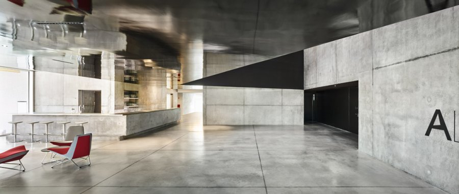 Le hall est le cœur du projet. Les surfaces de laque noire, associées à celles laissées en béton brut, animent et complexifient la perception de l’espace.