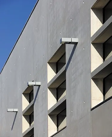 Façade sud, des brise- soleil en béton préfabriqués protègent les ouvertures du rayonnement tout en participant à leur redécoupage. e__ la casquette installée sur la façade arrière, côté stade, fait écho à celle marquant l’entrée principale dans le gymnase. f __ sur la façade arrière, côté buvette, gradins et rampe font le lien avec le stade existant. g __ f outre leur intérêt graphique, les leds insérées dans les trous de banche participent au rôle de signal du bâtiment. Façade sud, des brise- soleil en béton préfabriqués protègent les ouvertures du rayonnement tout en participant à leur redécoupage. e__ la casquette installée sur la façade arrière, côté stade, fait écho à celle marquant l’entrée principale dans le gymnase. f __ sur la façade arrière, côté buvette, gradins et rampe font le lien avec le stade existant. g __ f outre leur intérêt graphique, les leds insérées dans les trous de banche participent au rôle de signal du bâtiment.