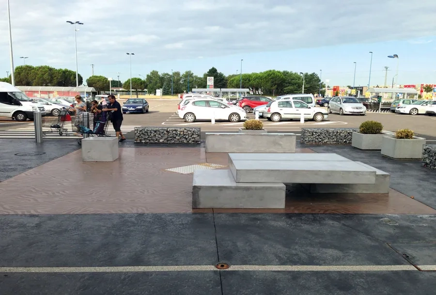 Le béton noir imprimé en motifs légers est traversé par une bande de guidage au sol pour sécuriser le déplacement des personnes aveugles ou malvoyantes (PAM). À l'arrière du banc en béton, une bande d'éveil à la vigilance (BEV). Le béton noir imprimé en motifs légers est traversé par une bande de guidage au sol pour sécuriser le déplacement des personnes aveugles ou malvoyantes (PAM). À l'arrière du banc en béton, une bande d'éveil à la vigilance (BEV).