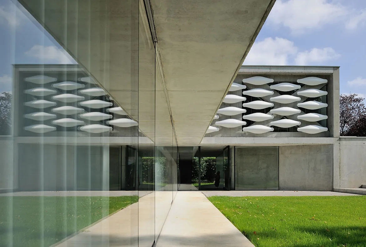 L’inflexion diagonale du mur en béton de la façade ouest au rezde-chaussée  indique l’emplacement de la porte d’entrée.