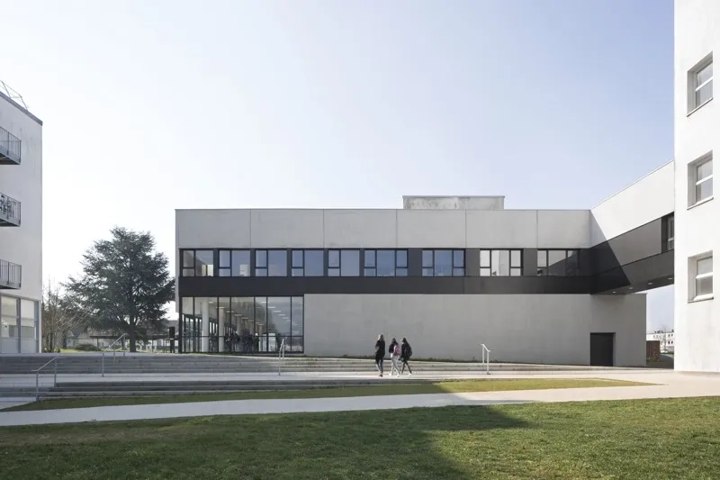 Les parois aveugles en béton brut matricé de la salle polyvalente ancrent l’édi ce dans le sol, tandis qu’à l’étage les salles de travail s’ouvrent par de généreuses baies vitrées sur la vue lointaine. Les parois aveugles en béton brut matricé de la salle polyvalente ancrent l’édi ce dans le sol, tandis qu’à l’étage les salles de travail s’ouvrent par de généreuses baies vitrées sur la vue lointaine.