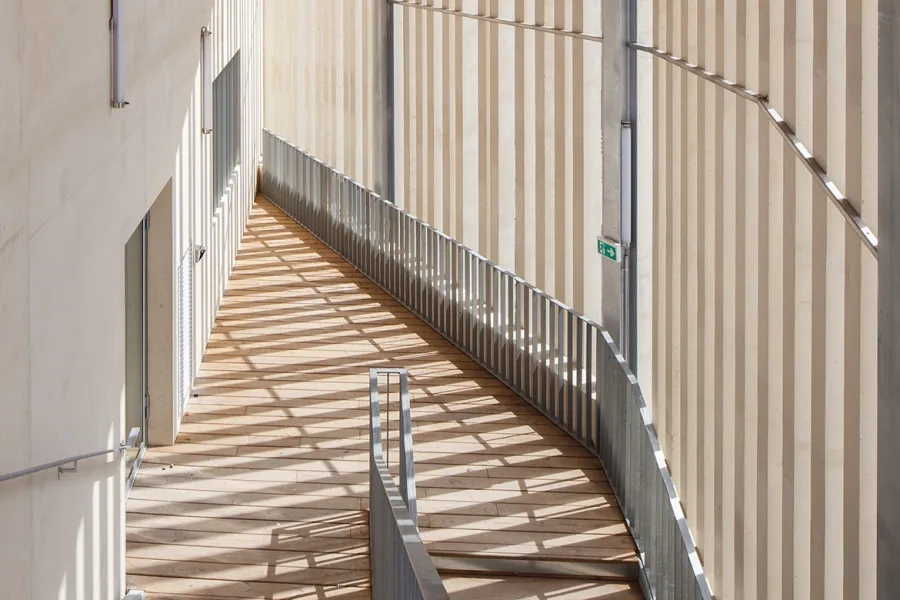 Les lames béton des claustras, réalisées en préfabrication foraine, permettent de créer une enveloppe continue qui intègre les espaces de circulation à la volumétrie générale.  