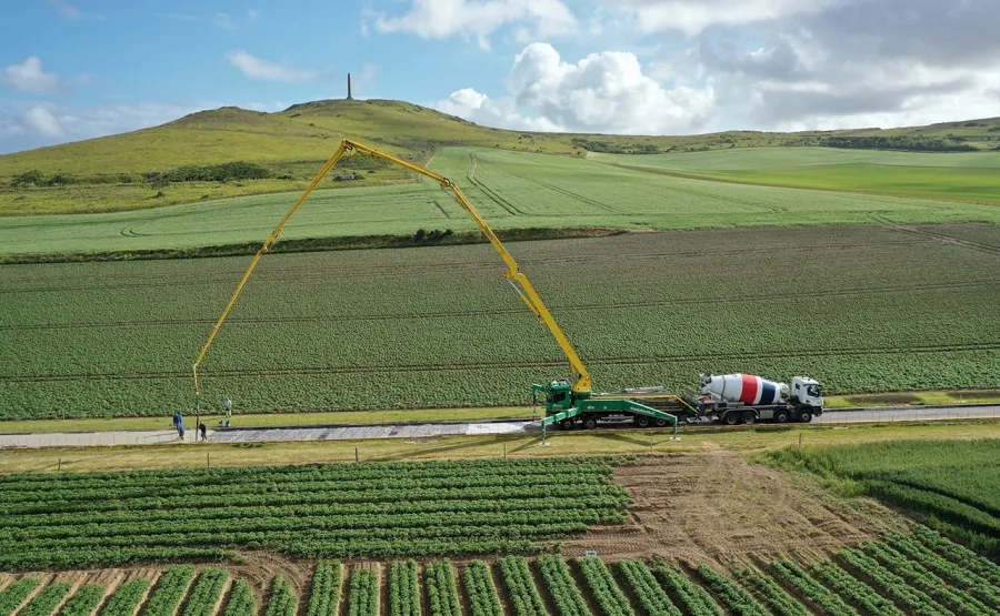 Coulage du béton sur la rue de la Mer avec vue sur le cap Blanc-Nez et l’obélisque à la mémoire de la Dover Patrol. Le débattement de la pompe limite le coulage à des sections de 60 mètres par jour (environ 270 m², soit la capacité de six ou sept toupies). Coulage du béton sur la rue de la Mer avec vue sur le cap Blanc-Nez et l’obélisque à la mémoire de la Dover Patrol. Le débattement de la pompe limite le coulage à des sections de 60 mètres par jour (environ 270 m², soit la capacité de six ou sept toupies).