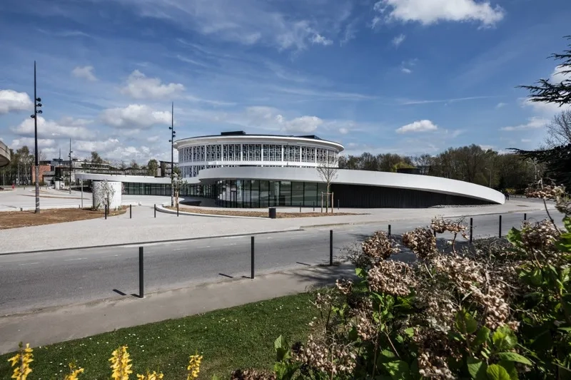 L’acrotère blanc en béton dessine un renfoncement qui libère au sol un vaste parvis. L’acrotère blanc en béton dessine un renfoncement qui libère au sol un vaste parvis.