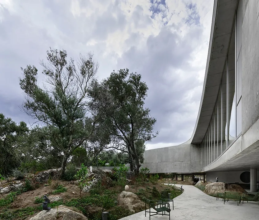Le béton des façades et du sol semble couler dans le terrain et délimiter le jardin.