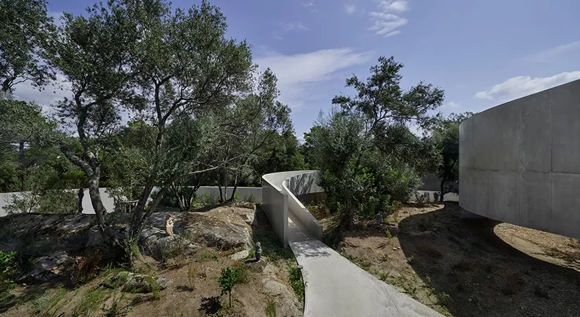 Les courbes de la rampe et du mur d’enceinte se glissent entre les rochers du terrain.