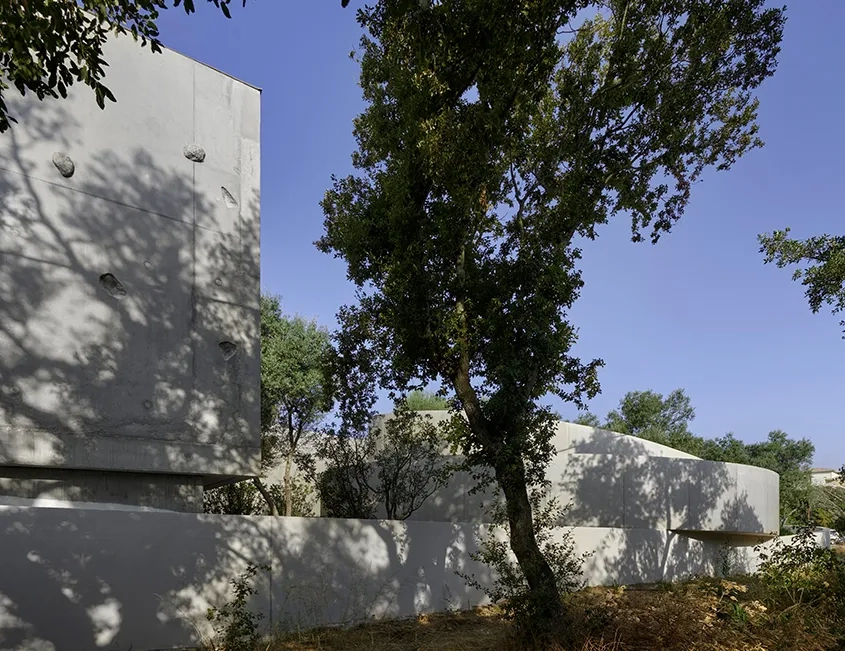 Les arbres du site impriment leurs ombres changeantes sur la peau en béton brut de la médiathèque.