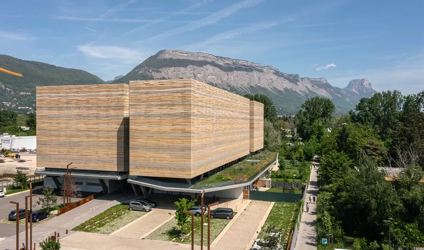 Par la matérialité et les variations de teintes des voiles de béton qui le recouvrent, le bâtiment s’accorde aux massifs montagneux qui l’entourent.