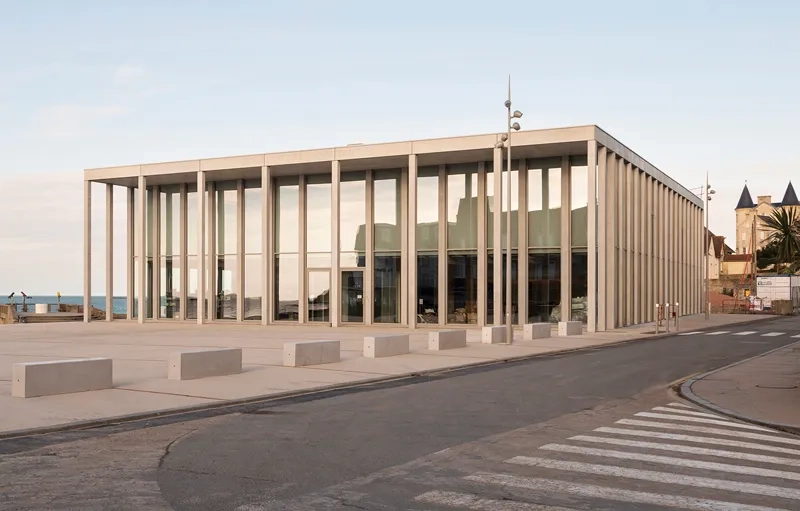 La position centrale de l'exosquelette de béton définit les deux espaces publics du grand parvis en béton sablé couleur sable micro-désactivé et du jardin qui longe la cale à l'arrière.