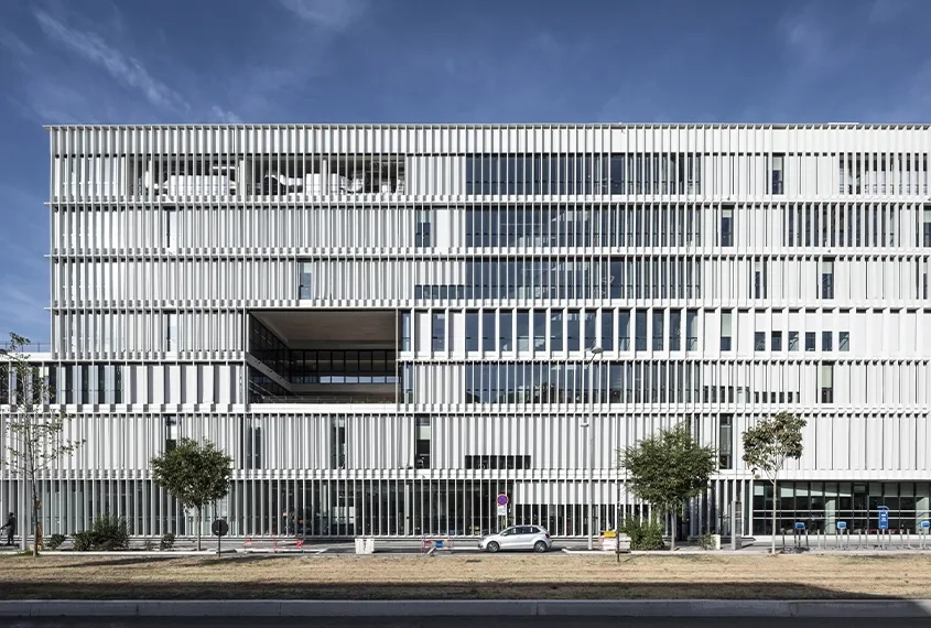 Orientée à l’est, la façade principale est protégée de l’ensoleillement direct par des brise-soleil verticaux réalisés en BFUP et associés à des stores extérieurs motorisés.