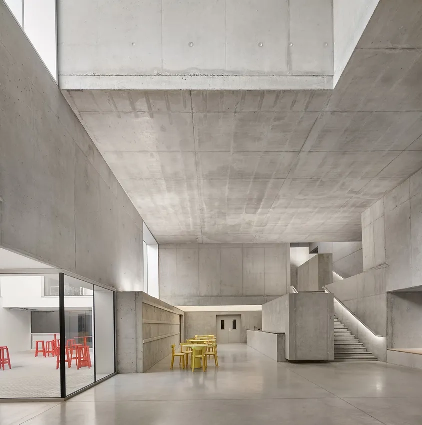 La masse sculpturale du béton qui forme le dessin du mobilier du bar accompagne également la montée de l'escalier vers la bibliothèque.