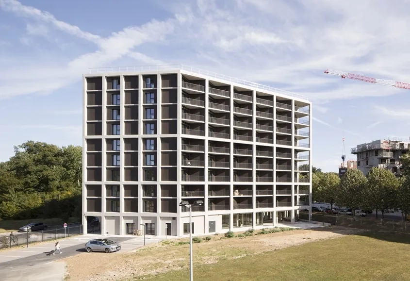 Le rythme des lignes verticales et horizontales en béton donne son unité à l’édifice et affiche sa présence dans le site, quelle que soit l’orientation. Le rythme des lignes verticales et horizontales en béton donne son unité à l’édifice et affiche sa présence dans le site, quelle que soit l’orientation.