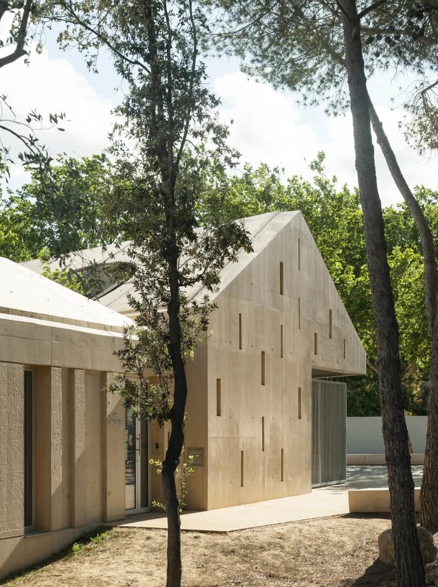 La façade extérieure joue un rôle de « gangue » protectrice. La teinte calcaire du béton résonne avec les teintes naturelles et chaleureuses du site.