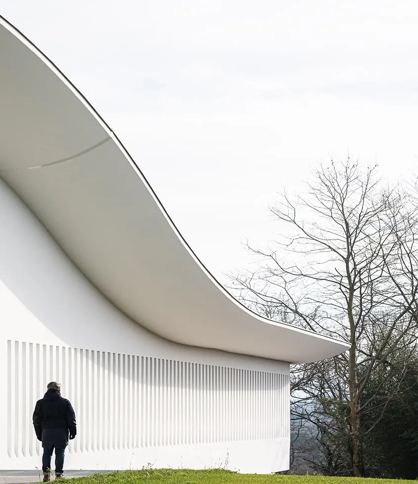 Des failles verticales marquent l’épaisseur de la façade ouest. Le béton de teinte blanche participe de la régulation thermique du bâtiment.