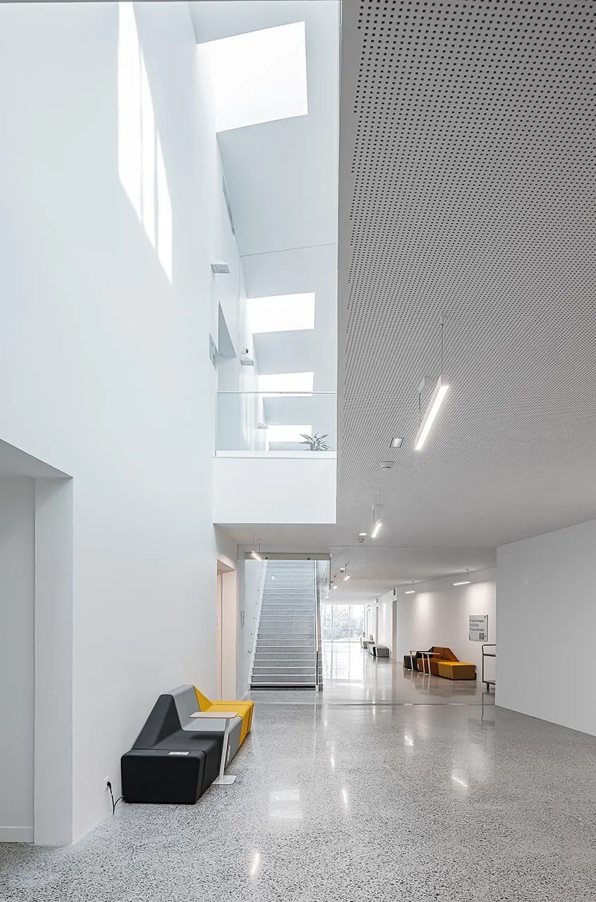 Circulation centrale du rez-de-jardin, éclairée à travers les grandes trémies surplombées de lanterneaux.