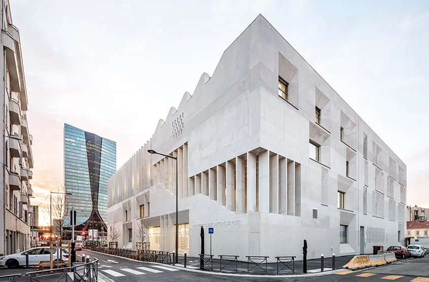 Sur l’avenue Salengro et la rue Urbain V, le bâtiment se perçoit comme un monolithe sculpté en béton clair. Sur l’avenue Salengro et la rue Urbain V, le bâtiment se perçoit comme un monolithe sculpté en béton clair.
