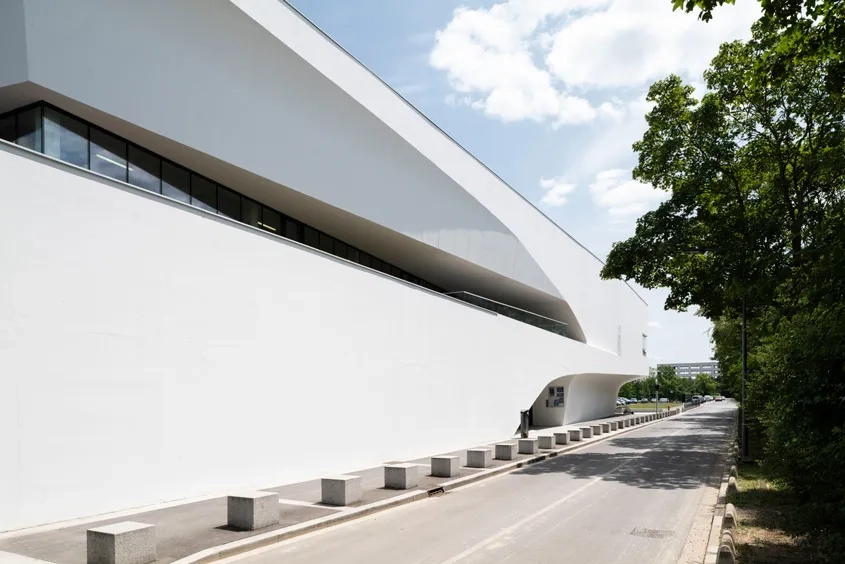 Gymnase – En partie haute du gymnase, une profonde découpe abrite une terrasse qui est accessible depuis le haut des gradins.