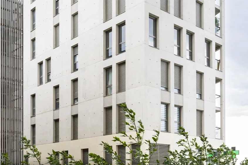 Les façades de béton grège sont rythmées par le matriçage des impostes.