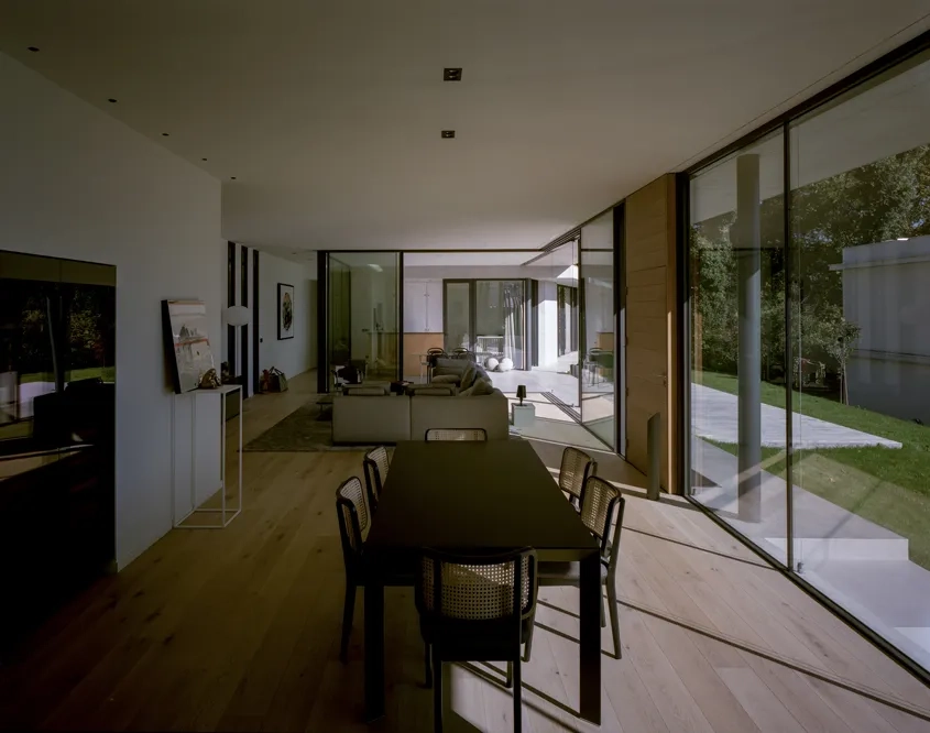 Dans l'espace à vivre, la porte en bois et le parquet marquent un contraste avec les emmarchements et le débord de toiture en béton.