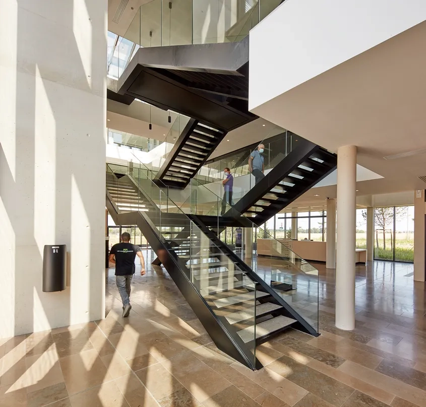 À l’articulation des deux ailes de bureaux, le hall d’entrée se développe en hauteur autour d’un vide sur trois niveaux.