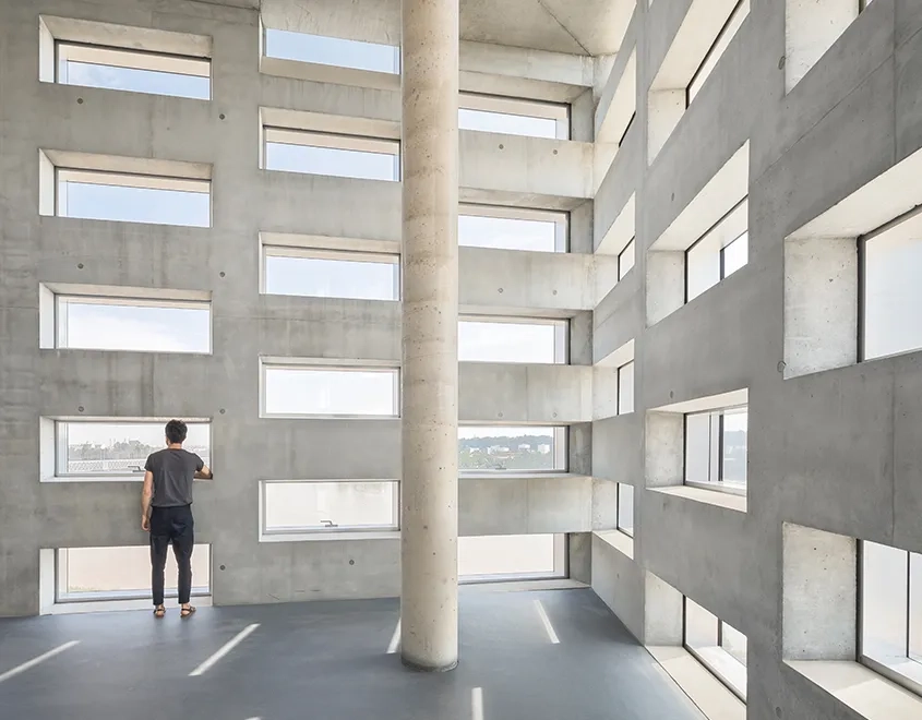 Dans les espaces du bureau, les matériaux sont laissés bruts. L’épaisseur des façades de béton laisse pénétrer la lumière tout en faisant brise-soleil. Dans les espaces du bureau, les matériaux sont laissés bruts. L’épaisseur des façades de béton laisse pénétrer la lumière tout en faisant brise-soleil.