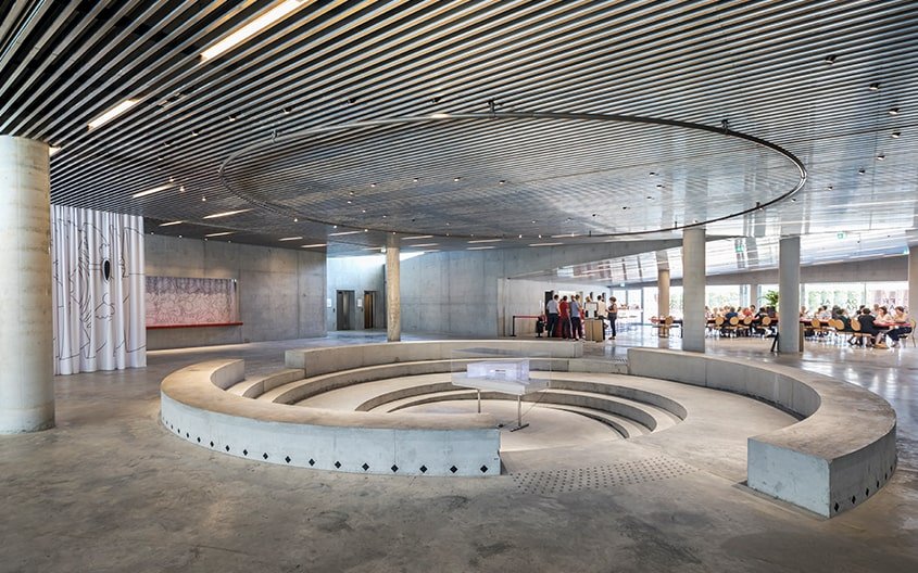 L’espace central du hall commun conçu en agora s’inscrit dans le sol avec ses gradins circulaires de béton brut.