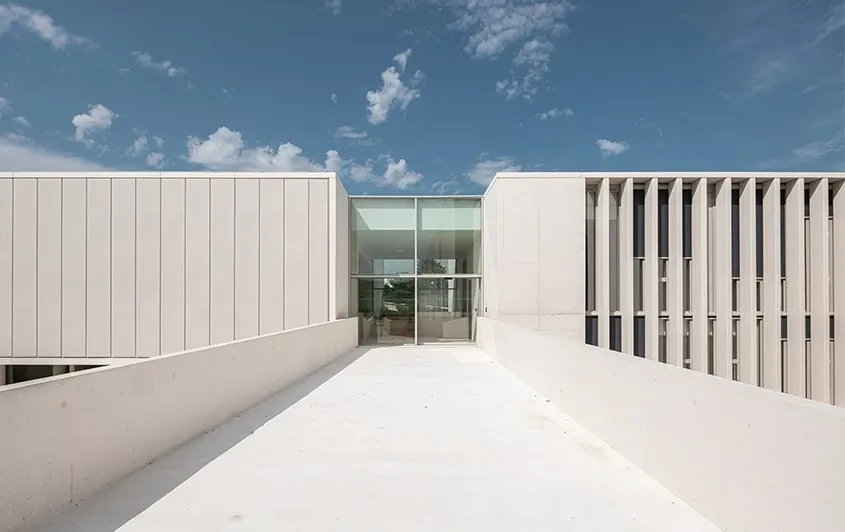 De grandes ventelles réalisées en béton blanc et préfabriquées protègent les surfaces vitrées de l’ensoleillement direct.