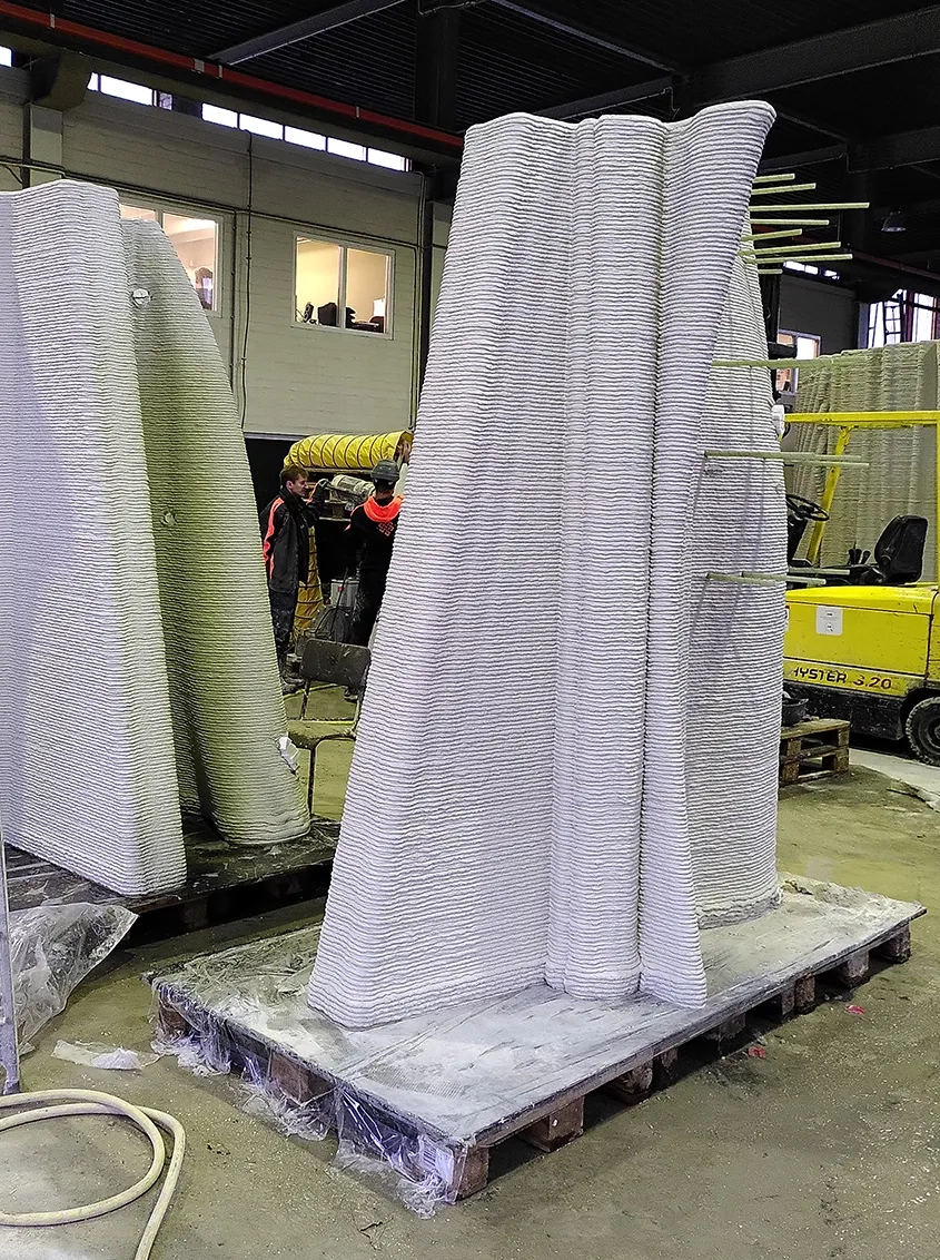 Des coques en béton imprimées 3D par dépôt de couches successives sont apposées sur la structure en béton armé pour servir de coffrage.