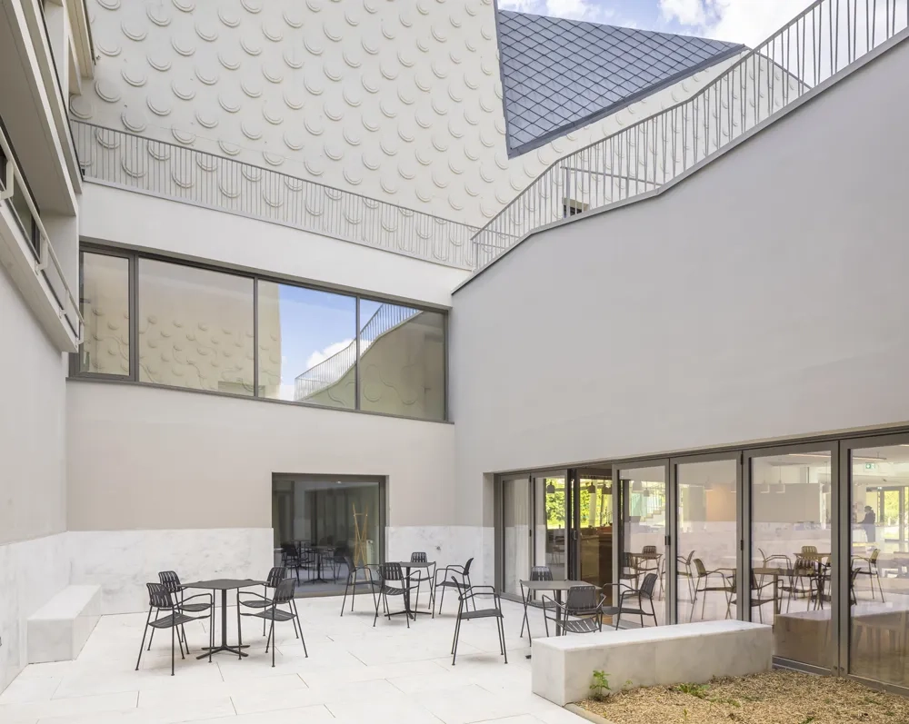 Un patio accessible ménage un lien visuel entre la salle d’animation, avec le bar, et les loges privées.
