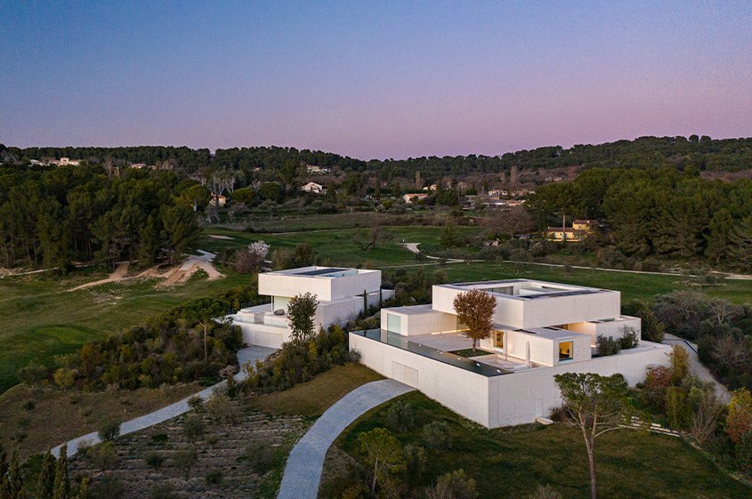 Les volumes en béton blanc des villas émergent de la végétation méditerranéenne.
