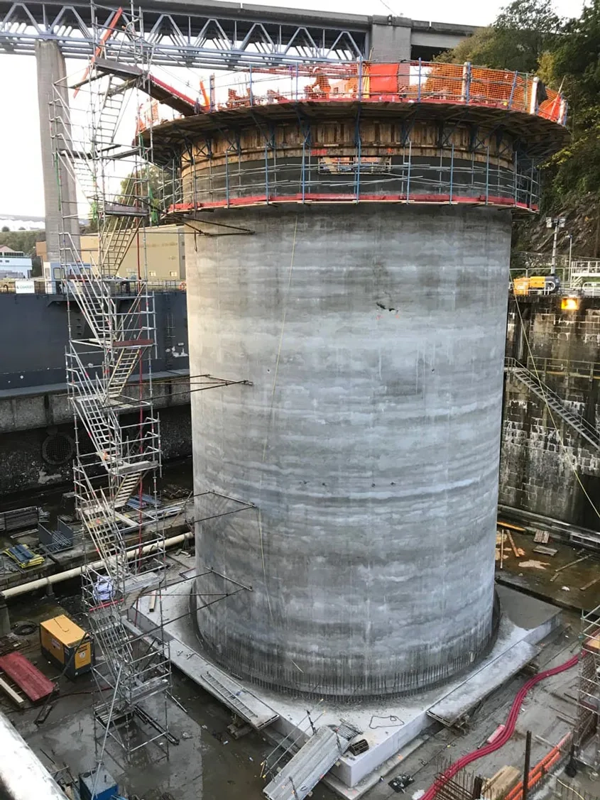 Encastré dans un radier de 80 cm d’épaisseur, le voile circulaire du musoir (40 cm d’épaisseur) a été érigé à l’aide d’un coffrage glissant sur toute sa hauteur (22,2 m). Le coulage du voile a été mis en œuvre en continu sur six jours par une équipe de 40 personnes mobilisées 24 h/24. Cette continuité permettait de limiter les reprises de bétonnage, qui constituent des zones de fragilité, notamment vis-à-vis de l’étanchéité du parement. Encastré dans un radier de 80 cm d’épaisseur, le voile circulaire du musoir (40 cm d’épaisseur) a été érigé à l’aide d’un coffrage glissant sur toute sa hauteur (22,2 m). Le coulage du voile a été mis en œuvre en continu sur six jours par une équipe de 40 personnes mobilisées 24 h/24. Cette continuité permettait de limiter les reprises de bétonnage, qui constituent des zones de fragilité, notamment vis-à-vis de l’étanchéité du parement.
