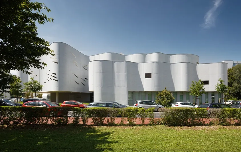Les façades ondulantes en béton deviennent sculpture urbaine, changeante au fil des heures et du niveau d’éclairement. Les façades ondulantes en béton deviennent sculpture urbaine, changeante au fil des heures et du niveau d’éclairement.