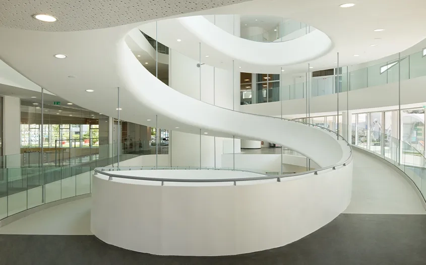 Au cœur du bâtiment, la grande rampe hélicoïdale relie et dessert les étages. Au cœur du bâtiment, la grande rampe hélicoïdale relie et dessert les étages.