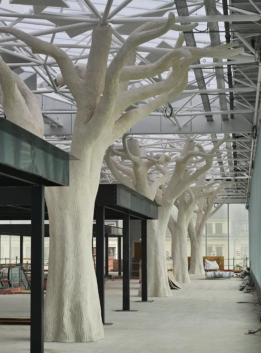 À 10 m du sol, la couverture de la mezzanine est portée par une allée d’arbres en béton projeté. À 10 m du sol, la couverture de la mezzanine est portée par une allée d’arbres en béton projeté.