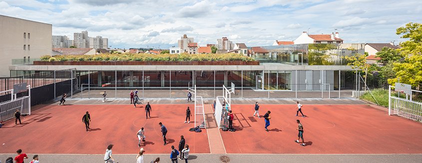La dalle de toiture en béton du gymnase, soulevée au-dessus du sol,  accueille un jardin.