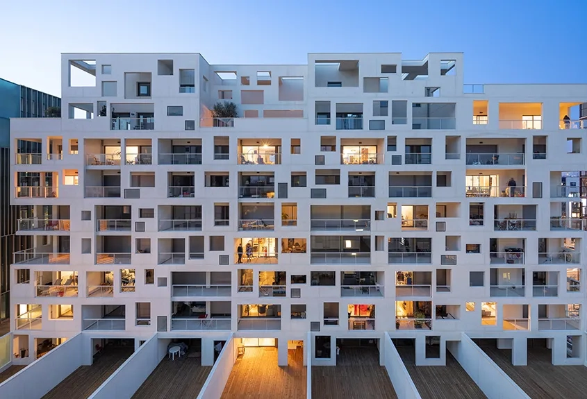 L’opération combine des logements, enserrés dans une résille porteuse en béton blanc autoplaçant, des bureaux, enveloppés par un mur rideau en aluminium, et des commerces en rez-de-chaussée. L’opération combine des logements, enserrés dans une résille porteuse en béton blanc autoplaçant, des bureaux, enveloppés par un mur rideau en aluminium, et des commerces en rez-de-chaussée.