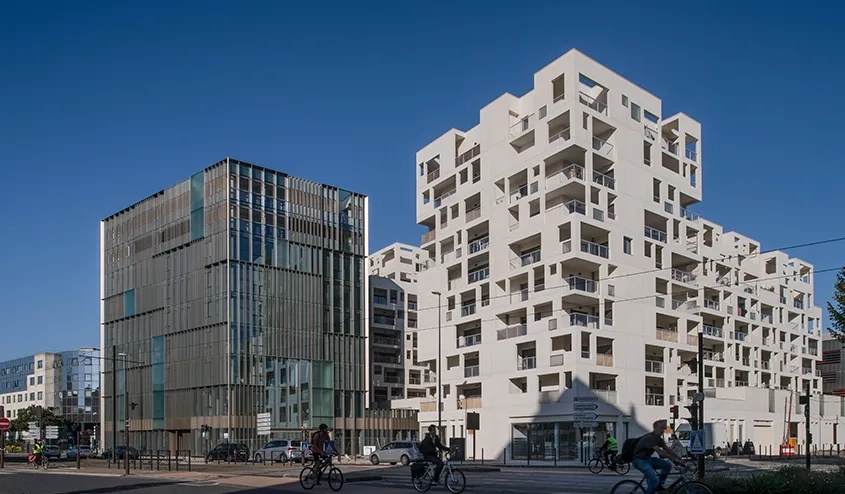 L’opération combine des logements, enserrés dans une résille porteuse en béton blanc autoplaçant, des bureaux, enveloppés par un mur rideau en aluminium, et des commerces en rez-de-chaussée. L’opération combine des logements, enserrés dans une résille porteuse en béton blanc autoplaçant, des bureaux, enveloppés par un mur rideau en aluminium, et des commerces en rez-de-chaussée.