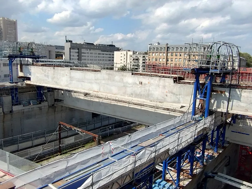 Des portiques de levage situés de part et d’autre de la méga-poutre permettent de descendre celle-ci jusqu’à sa position définitive, par l’intermédiaire de chevêtres brêlés à la structure par des barres précontraintes.