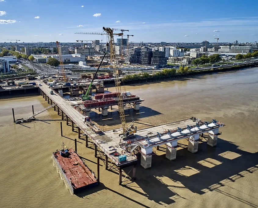 Les travaux de fondations et d’élévation des piles sont réalisés depuis des estacades (perpendiculaires au fleuve) et des épis (parallèles) provisoires.