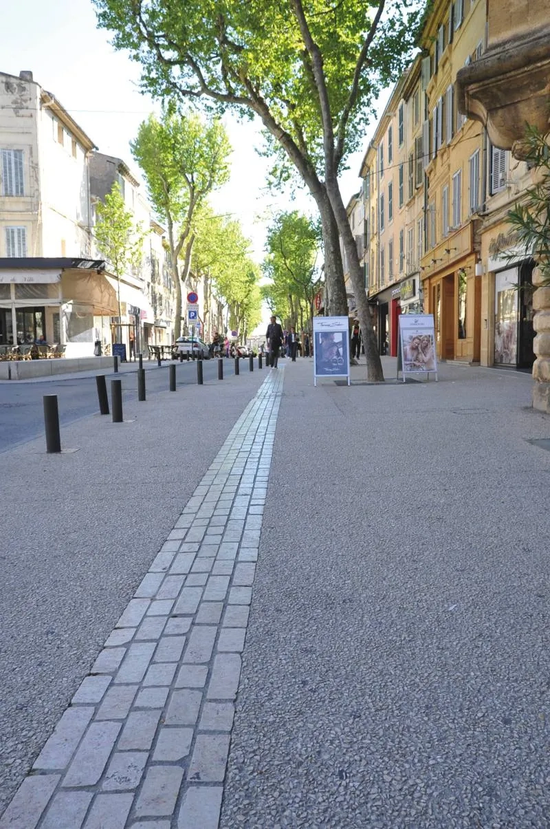 Le calepinage des bandes structurantes en pierre Cénia rythme les différents espaces (terrasses de café, fontaines) et les trottoirs qui ont été élargis. Le calepinage des bandes structurantes en pierre Cénia rythme les différents espaces (terrasses de café, fontaines) et les trottoirs qui ont été élargis.