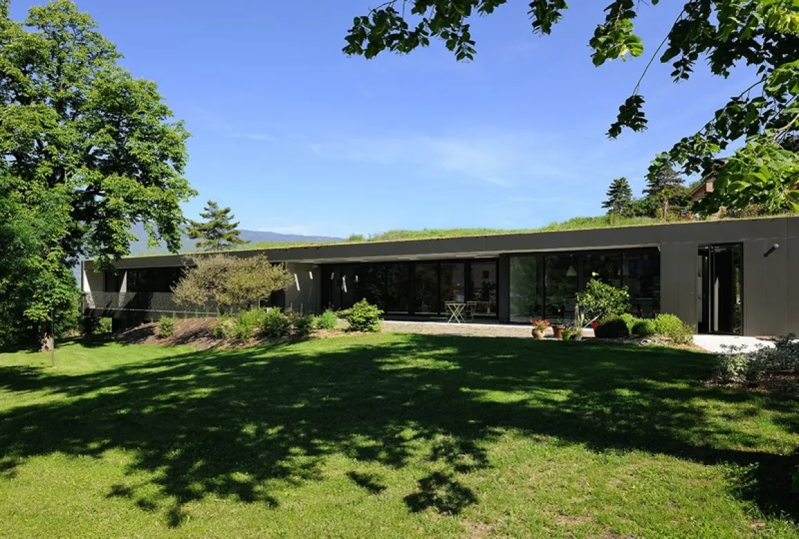 La maison tourne volontairement le dos aux constructions avoisinantes, côté nord, a n d’orienter tous les espaces vers le sud et les vues dégagées sur le paysage. La toiture- terrasse est entièrement végétalisée de façon intensive.